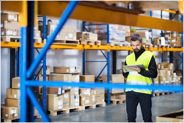 An expert in plant and mechanical engineering is standing in the warehouse with a tablet